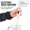 Hand holding Yozcoffee electric milk frother frothing milk in a clear glass pitcher for latte and cappuccino